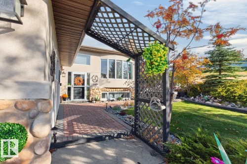 Stucco exterior with stone accenting, brick paver walkway, decorative trellis, and mature landscaping - 5502 48 Avenue, Beaumont, AB 