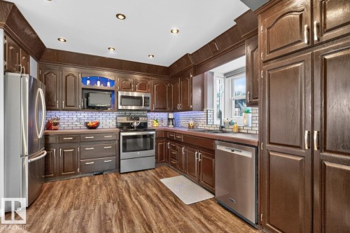 Kitchen featuring wood-finish cabinetry, stainless steel appliances, wood-finish flooring, and recessed ceiling lighting - 5502 48 Avenue, Beaumont, AB 