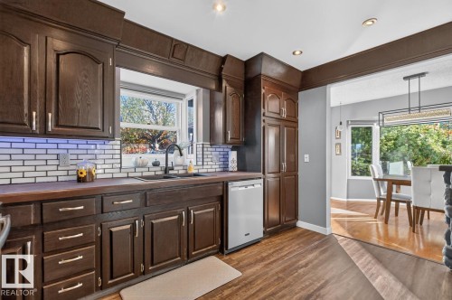 Dark wood-finish cabinetry, subway tile backsplash, integrated sink with matte black faucet, recessed lighting, and wood-finish flooring - 5502 48 Avenue, Beaumont, AB 