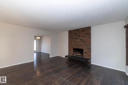 Brick fireplace with a dark tile hearth, wood-finish flooring, and neutral wall paint - 17311 107 Street Nw, Edmonton, AB 