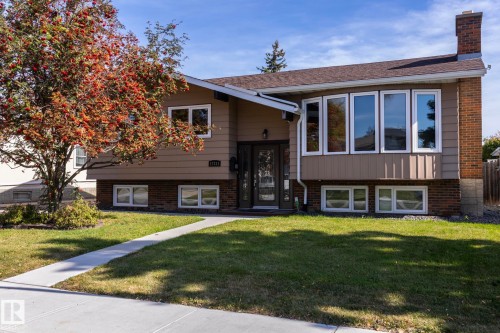 Split-level residence featuring a brick and siding exterior, multiple windows, and an established front lawn - 17311 107 Street Nw, Edmonton, AB 