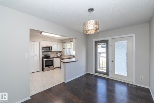 Dark wood-finish flooring with a decorative overhead light fixture - 17311 107 Street Nw, Edmonton, AB 