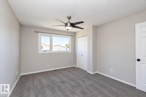 Light gray walls, textured ceiling, gray carpet, white trim, and a ceiling fan with integrated lighting - 17311 107 Street Nw, Edmonton, AB 