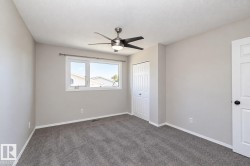 Light gray walls, textured ceiling, gray carpet, white trim, and a ceiling fan with integrated lighting - 