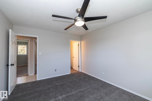 Recessed ceiling, neutral wall tones, modern ceiling fan with integrated lighting, dark gray carpeting, and white panel doors - 17311 107 Street Nw, Edmonton, AB 