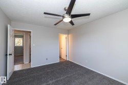 Recessed ceiling, neutral wall tones, modern ceiling fan with integrated lighting, dark gray carpeting, and white panel doors - 
