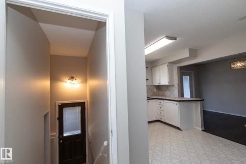 Kitchen featuring white cabinetry, patterned floor tile, and a tile backsplash - 17311 107 Street Nw, Edmonton, AB 