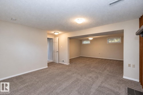 Spacious room featuring neutral carpet flooring, recessed windows, and flush-mount ceiling lights - 17311 107 Street Nw, Edmonton, AB 