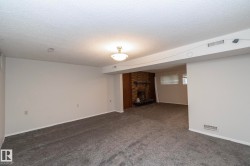 Spacious room with new gray carpeting, white painted walls, and a recessed fireplace with a brick surround - 