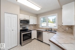 White cabinetry with black hardware, stainless steel appliances, tile flooring, and a double basin sink - 