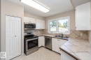 White cabinetry with black hardware, stainless steel appliances, tile flooring, and a double basin sink - 17311 107 Street Nw, Edmonton, AB 