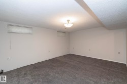 Spacious interior with gray carpeting, white walls, and a semi-flush mount ceiling fixture - 
