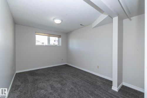 Neutral wall paint, textured ceiling, flush mount ceiling light, and a window with blinds - 17311 107 Street Nw, Edmonton, AB 