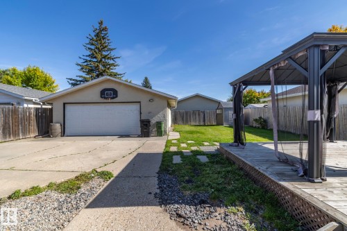 Expansive backyard featuring a wood deck with a gazebo, a detached garage with a concrete driveway, and a manicured lawn - 17311 107 Street Nw, Edmonton, AB 