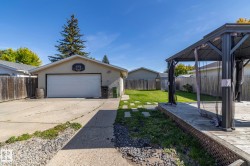 Expansive backyard featuring a wood deck with a gazebo, a detached garage with a concrete driveway, and a manicured lawn - 