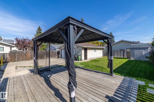 Wood deck with a metal gazebo, complemented by a grassy yard, a detached garage, and a storage shed - 17311 107 Street Nw, Edmonton, AB 
