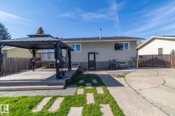 Expansive backyard featuring a multi-level wood deck with a gazebo, a concrete patio, and a grass pathway - 