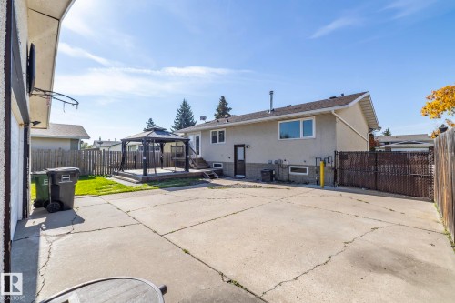 Spacious concrete patio with an elevated wooden deck featuring a gazebo, and a secure fenced perimeter - 17311 107 Street Nw, Edmonton, AB 