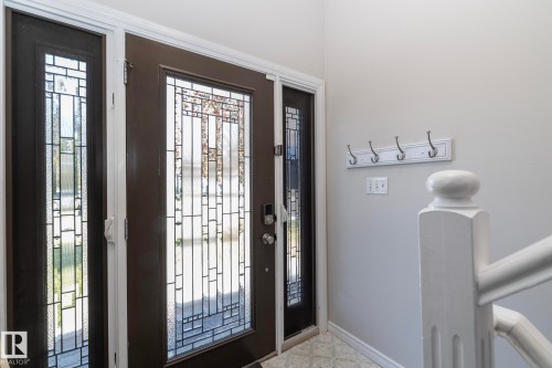 Entryway featuring a dark-framed door with decorative glass, coordinating sidelight, and tiled flooring - 17311 107 Street Nw, Edmonton, AB 