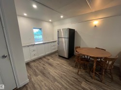 Stainless steel refrigerator, wood-finish flooring, white cabinetry, light-toned countertop - 