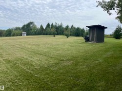 Expansive lawn area with a small detached structure and a secondary shed - 