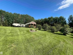 Expansive green lawn with a natural tree line backdrop - 