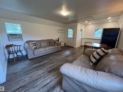 Wood-finish flooring, recessed lighting, ceiling-mounted light fixture, white walls, and a multi-pane door - 