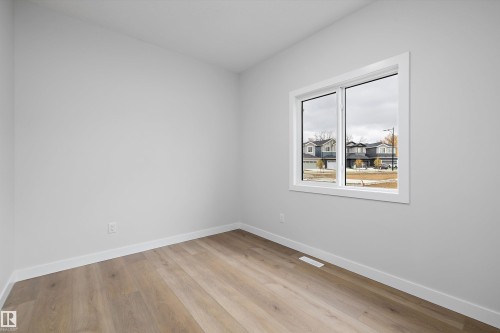Neutral-toned room with wood-finish flooring and a single-pane casement window featuring white trim - Edmonton, AB 