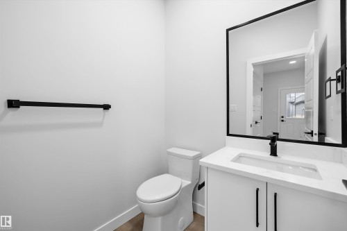 White vanity with stone-composite countertop, undermount sink, matte black faucet, and framed rectangular mirror, featuring matte black hardware and towel bar - Edmonton, AB 