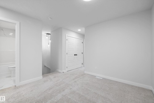 Neutral-toned carpeting, white interior doors with multi-panel detailing, recessed lighting, and a multi-pendant light fixture - Edmonton, AB 