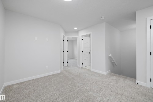 Neutral-toned wall-to-wall carpeting, recessed ceiling lighting, and solid-core interior doors with matte black hardware - Edmonton, AB 