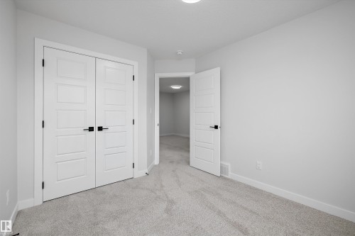 Room featuring wall-to-wall carpeting, white four-panel interior doors, and matte black hardware - Edmonton, AB 