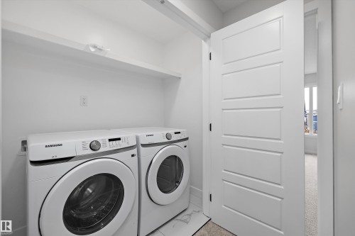 Laundry space featuring built-in shelving, white five-panel interior door, and tile flooring - Edmonton, AB 