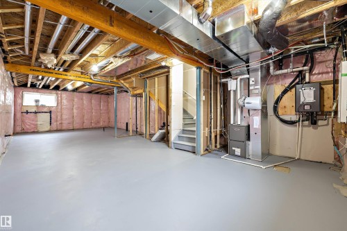 Unfinished lower level featuring exposed wood framing, painted concrete flooring, installed HVAC ductwork, and wall-mounted mechanical systems - Edmonton, AB 