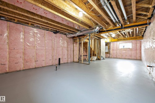 Unfinished lower level featuring exposed wood joist ceilings, insulated wall panels, concrete flooring, and metallic ductwork - Edmonton, AB 