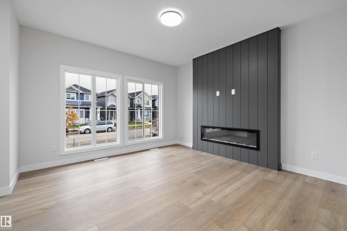 Interior featuring wood-finish flooring, dual windows, and a floor-to-ceiling charcoal shiplap accent wall with a built-in linear electric fireplace - Edmonton, AB 