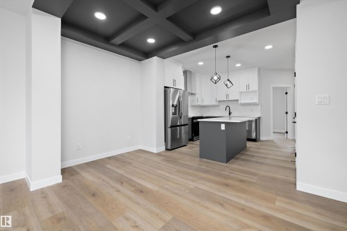 Coffered ceiling with recessed lighting, wood-finish flooring, kitchen island, shaker-style cabinetry, and stainless steel appliances - Edmonton, AB 