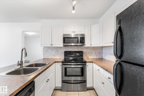 Kitchen featuring white cabinetry, stainless steel appliances, laminate countertops, a double-basin sink with a gooseneck faucet, and tiled flooring - #109 4309 33 St, Stony Plain, AB 