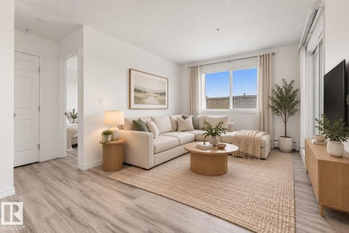 Neutral interior featuring light-tone wood-finish flooring, sliding glass door, and large window with adjustable horizontal blinds - #109 4309 33 St, Stony Plain, AB 