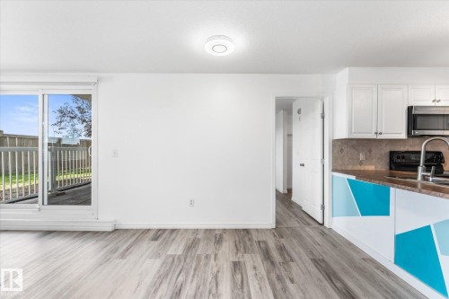 Sliding glass door, wood-finish flooring, white cabinetry, integrated microwave, and neutral wall surfaces - #109 4309 33 St, Stony Plain, AB 