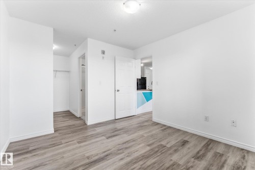 Room featuring wood-finish flooring, a flush-mount ceiling light fixture, and a built-in closet with overhead shelving - #109 4309 33 St, Stony Plain, AB 