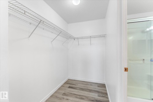 Walk-in storage space featuring wood-finish flooring, white walls, and tiered metal shelving - #109 4309 33 St, Stony Plain, AB 
