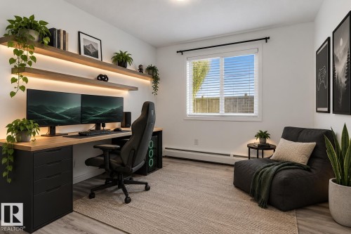 Room featuring wood-finish floating shelving with integrated under-cabinet lighting, neutral walls, sliding window with horizontal blinds, and wood-finish flooring - #109 4309 33 St, Stony Plain, AB 