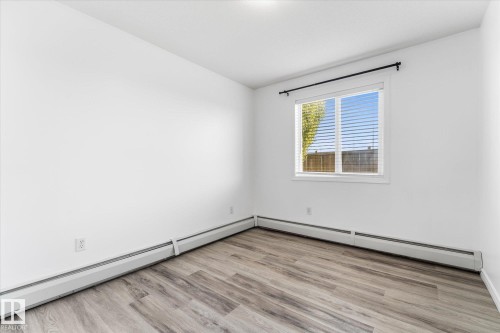 Room featuring wood-finish flooring, white walls, and a window with horizontal blinds - #109 4309 33 St, Stony Plain, AB 