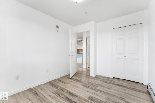 Neutral walls featuring wood-finish flooring, white panel doors, and a double-door closet - #109 4309 33 St, Stony Plain, AB 