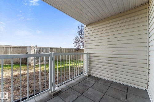 Covered patio featuring concrete tile flooring, vinyl siding, and a white metal railing enclosure - #109 4309 33 St, Stony Plain, AB 
