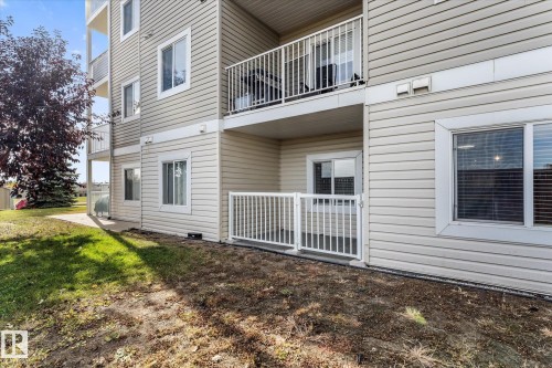 Exterior featuring beige horizontal siding, a private ground-level patio with white metal railing, and a second-story balcony with white metal railing - #109 4309 33 St, Stony Plain, AB 