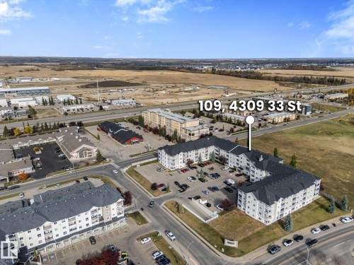 Aerial view of a multi-level residential complex featuring asphalt shingle roofing, private balconies, and dedicated surface parking - #109 4309 33 St, Stony Plain, AB 