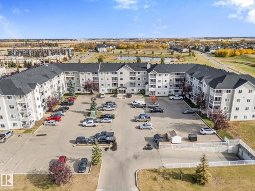 Multi-story residential building featuring a peaked roofline, private balconies, on-site paved parking, and landscaped grounds - #109 4309 33 St, Stony Plain, AB 
