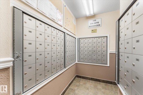 Dedicated mailroom featuring multiple banks of individual locking metal mailboxes, overhead fluorescent lighting, and tile flooring - #109 4309 33 St, Stony Plain, AB 
